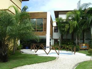 a villa with a resort with palm trees in front of it at Apartamento Enseada Praia do Forte in Praia do Forte