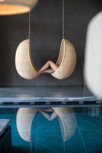 a woman is sitting in a hammock over a swimming pool at VillaVerde Aparthotel in Lagundo
