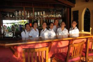 un grupo de mujeres con camisas blancas de pie detrás de un bar en Rikitikitavi en Kampot