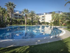a swimming pool at a resort with palm trees and a building at Dorasal Solo Familias Serviplaya in Playa de Xeraco
