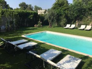 a swimming pool with chaise lounges and chairs in a yard at Villa Louise-Rose in Villeneuve-Loubet
