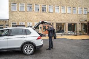 un hombre de pie junto a un coche con su baúl abierto en Second Home Apartments Asplund, en Solna