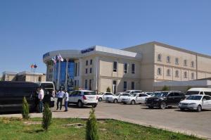 un gran edificio con coches estacionados en un estacionamiento en Hotel Uzbekistan, en Urganch