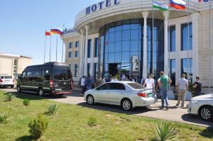 un gruppo di persone che si trovano fuori da un hotel con un autobus di Hotel Uzbekistan a Urganch