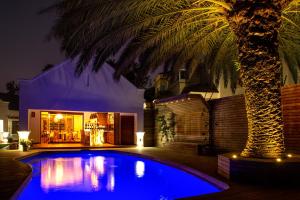 een palmboom voor een huis met een zwembad bij The Giglio Boutique Hotel in Johannesburg