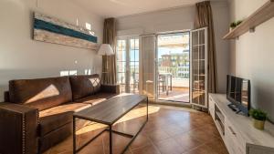 a living room with a couch and a television at Apartamentos Costaluz Las Dunas in Isla Canela