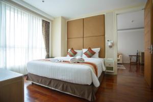 um quarto de hotel com uma cama grande e uma janela grande em GM Serviced Apartment (SHA Certified) em Bangkok
