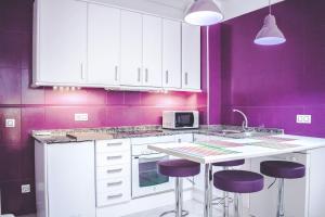 cocina púrpura con armarios blancos y paredes moradas en Alojamiento Lirio, Céntrico y cerca de la Playa en Vilanova i la Geltrú