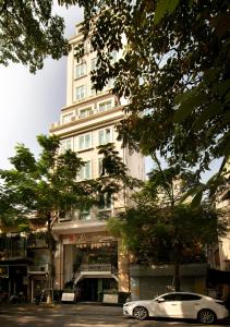 un coche blanco estacionado frente a un edificio alto en Anise Hotel & Spa Hanoi, en Hanói