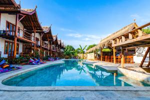 een zwembad in een resort met gebouwen bij Voodoo Gili in Gili Trawangan