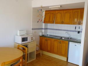 una pequeña cocina con armarios de madera y una mesa. en Brisas del Mar Azul, en Torrevieja