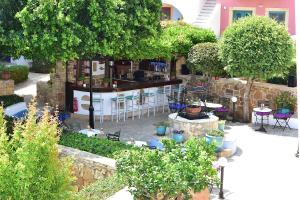 eine Außenterrasse mit Tischen, Stühlen und Bäumen in der Unterkunft Nefeli Hotel Leros in Agia Marina