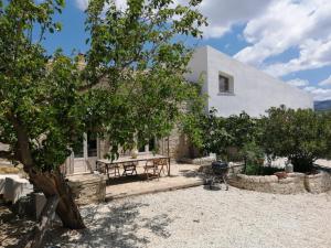 a white house with a picnic table and trees at Poggio del Gallo in Chiaramonte Gulfi