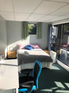 1 dormitorio con 1 cama y 1 silla en West Lake Holiday Home en Christchurch