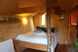 a bed in a cabin in a room with wooden walls at Domaine De Syam - Gîtes, Chambres d'hôtes & Cabanes in Syam