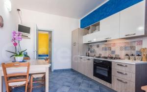 eine Küche mit weißen Schränken, einem Tisch und einem Herd in der Unterkunft Appartamento Da Maria in Torre Vado