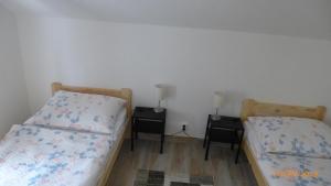 two beds in a room with two nightstands at Penzion Sklář in Nový Bor