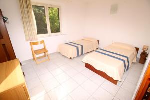 una camera con due letti e una sedia di Villa Badde rosa a Dorgali