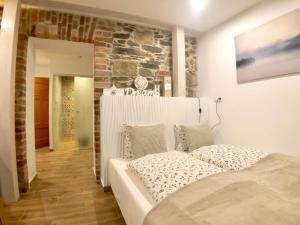 a white bed in a room with a stone wall at Ameisenberg Appartement in Oybin