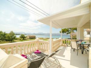 eine Veranda mit Stühlen und einem Tisch sowie Blick auf das Wasser in der Unterkunft Apartment in Alcúdia with Bay of Pollensa View in Alcúdia