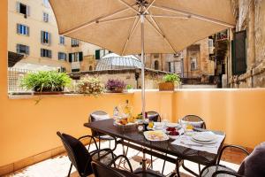 una mesa y sillas en un balcón con sombrilla en The Brunetti - Luxury serviced apartment, en Roma