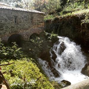 a waterfall on the side of a hill with a building at Watermill Moinho Garcia in Pinheiro da Bemposta