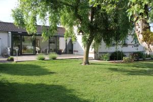 une maison avec un arbre en face d'une cour dans l'établissement La maison de TOINETTE, à Jonchery-sur-Suippe