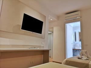 1 dormitorio con TV en la pared y 1 cama en Feel Good, en Rímini