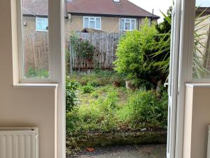 eine offene Tür zu einem Garten mit einem Zaun in der Unterkunft Marble Apartments Tooting House in London