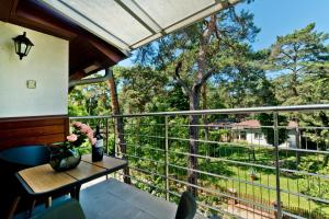 a balcony with a table and a view of a forest at Apartamenty.in Jurata in Jurata