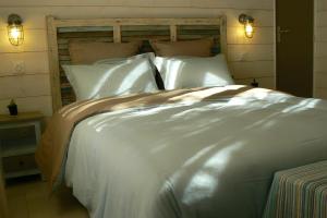 un grande letto con lenzuola e cuscini bianchi di L' Escale Tranquille a Sète