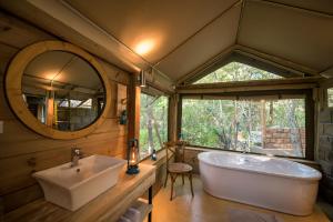 a bathroom with a tub and a sink and a mirror at Bundox Safari Lodge in Hoedspruit