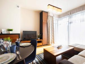 a living room with a table and a television at VacationClub – Diune Apartament 38 in Kołobrzeg