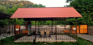 um gazebo com uma mesa e cadeiras e um telhado vermelho em Guesthouse Vashlovani em Lagodekhi