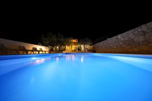 een groot zwembad dat 's nachts verlicht wordt bij Anna in Drage