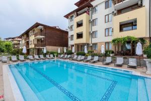 a swimming pool with chairs and a building at Garden of Eden Complex in Sveti Vlas