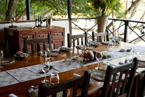 a wooden table with wine glasses on top of it at Ichingo Chobe River Lodge by Mantis in Punga +56 photos