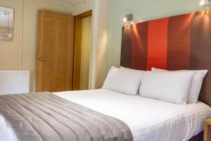 a bedroom with a white bed with a red headboard at Great Hallingbury Manor in Bishops Stortford