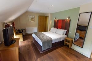 a hotel room with a bed and a television at Great Hallingbury Manor in Bishops Stortford