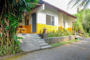 una casa gialla e bianca con scale di fronte di RedDoorz near STAB Syailendra Kopeng a Salatiga
