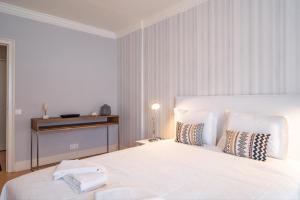 a white bedroom with a large white bed with pillows at Akisol Estoril Sunset in Estoril