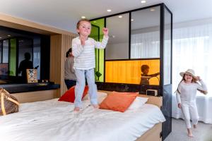 a boy and a girl jumping on a bed at Hotel Nelson in Knokke-Heist