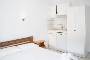 a white bedroom with a bed and a sink at Afroditi Pansion in Agios Nikitas