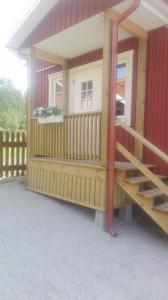 een klein huis met een veranda en een trap bij Dimgården in Leksand
