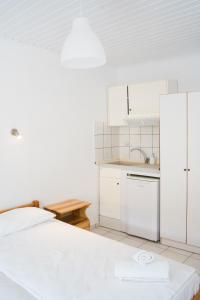a white kitchen with a bed and a sink at Afroditi Pansion in Agios Nikitas