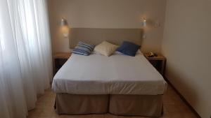 a bedroom with a large bed with blue and white pillows at Hotel Ristorante Il Gabbiano in Cecina