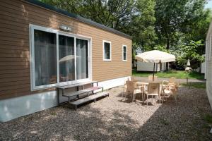 una casa pequeña con mesa, sillas y sombrilla en Camping Village Città di Milano, en Milán