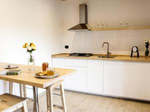 een keuken met witte kasten en een houten tafel bij La Dimora apartments in Siculiana