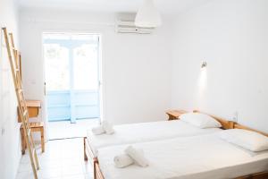 two beds in a white room with a window at Afroditi Pansion in Agios Nikitas