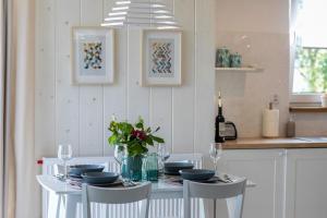 a white dining room with a white table with chairs at Tabaszówka in Krynica Zdrój